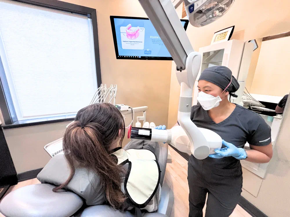 Dental team member taking an intraoral X-ray for a patient