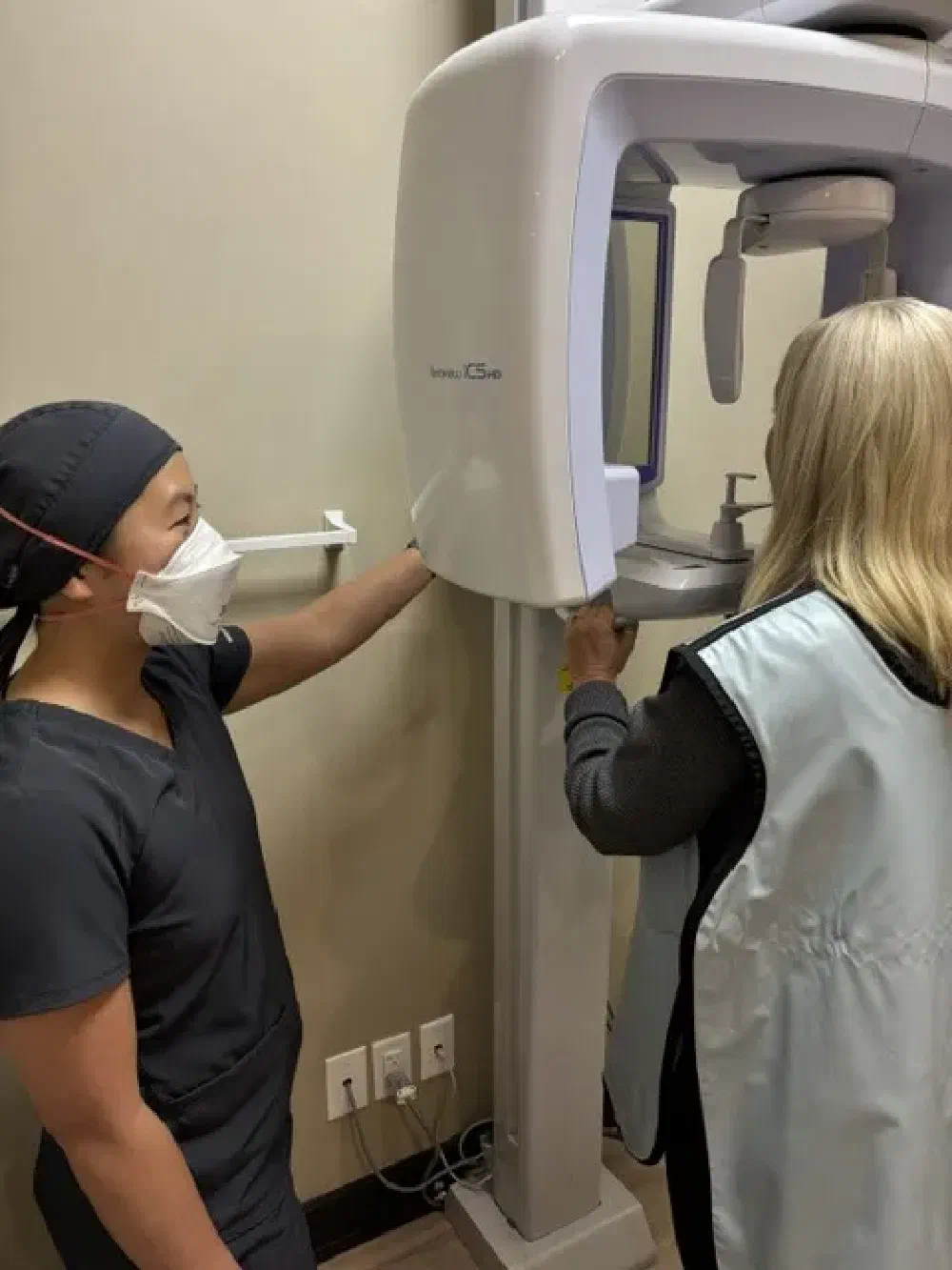 Dental team member assisting a patient with a panoramic dental X-ray