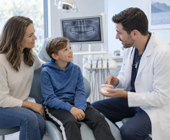 A child and parent talking with a dentist after a tooth injury