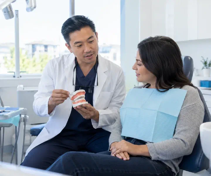A dentist reviewing urgent dental symptoms with a patient in an examination room