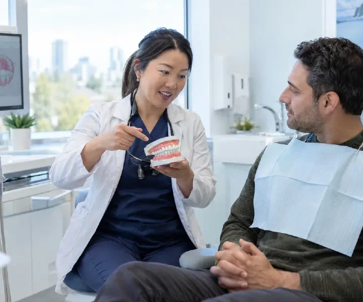 A dentist explaining a soft-tissue assessment and treatment plan to a patient