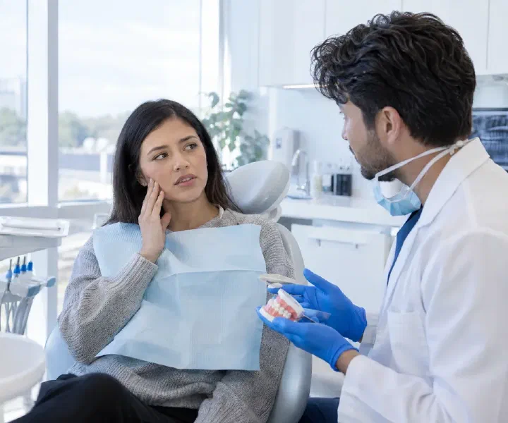 Dentist listening to a patient describe tooth pain during an urgent consultation