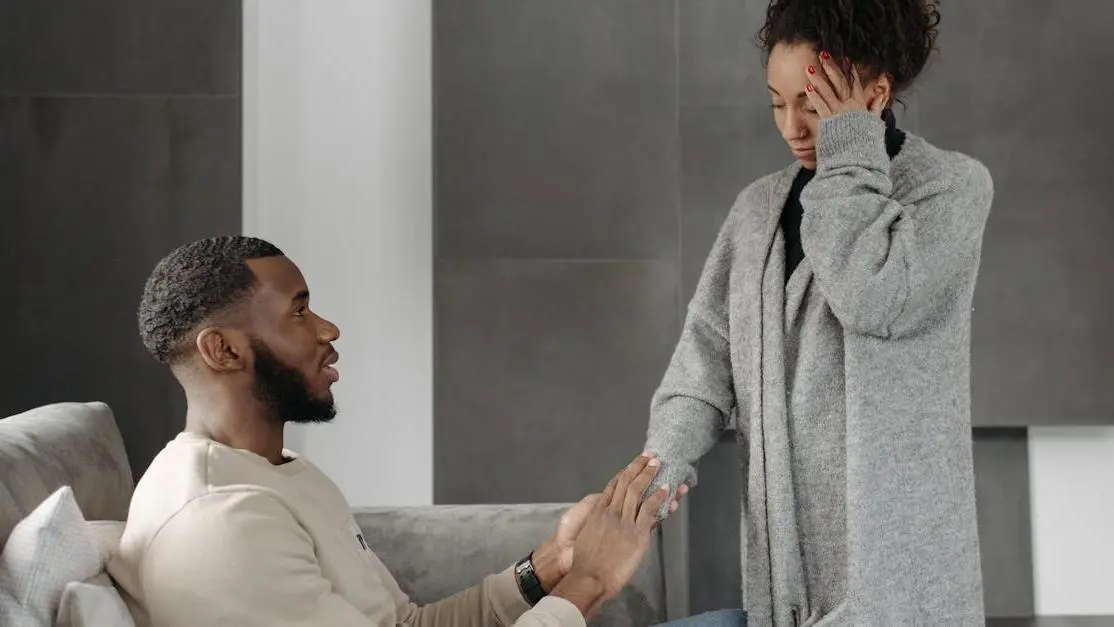 Man providing emergency tooth pain relief support to woman on sofa indoors.