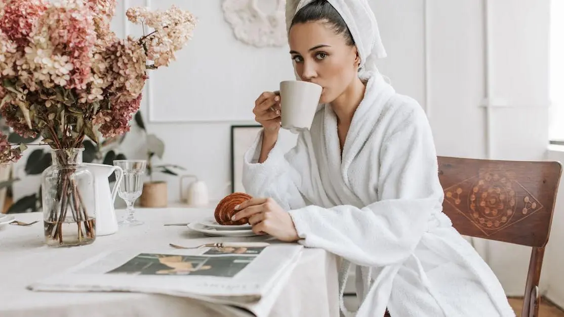 Woman having breakfast with coffee and croissant, relevant to eating after dental implant surgery.