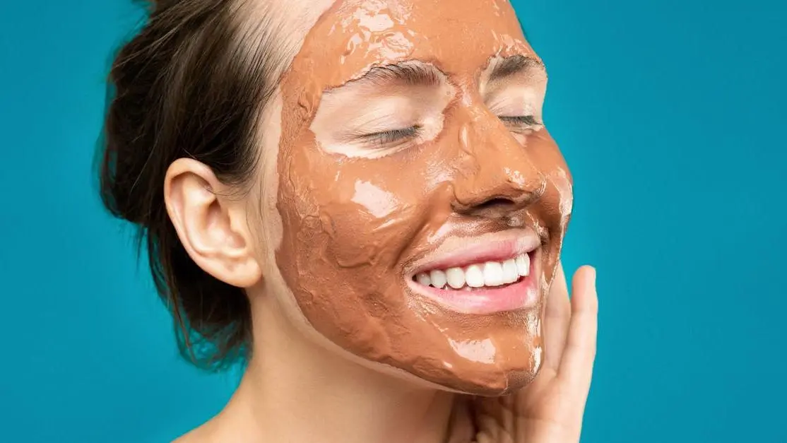 Woman with clay mud mask, smiling; related to how to treat receding gums.