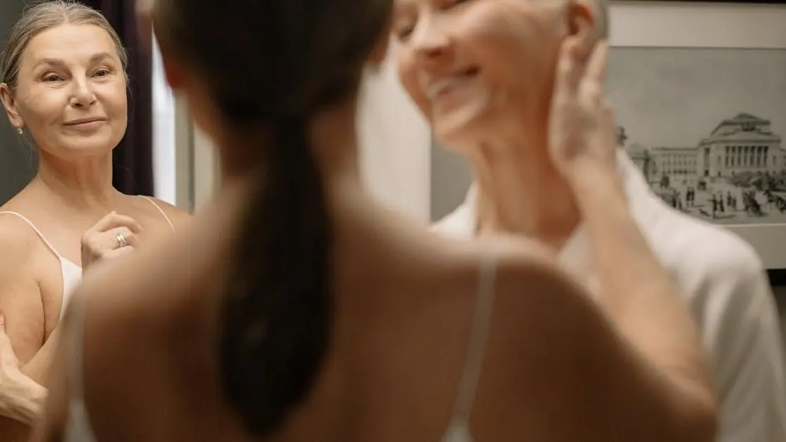 Smiling woman over 40 admiring her teeth in mirror, highlighting Invisalign timeline for adults over 40