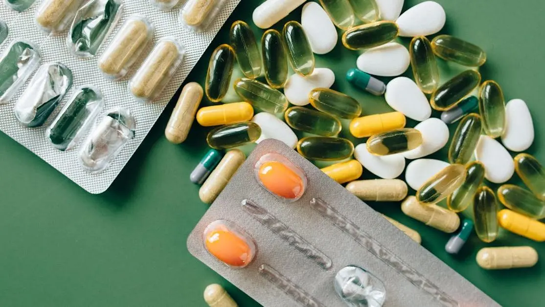 Variety of capsules and tablets related to medications that affect oral health on a green surface.