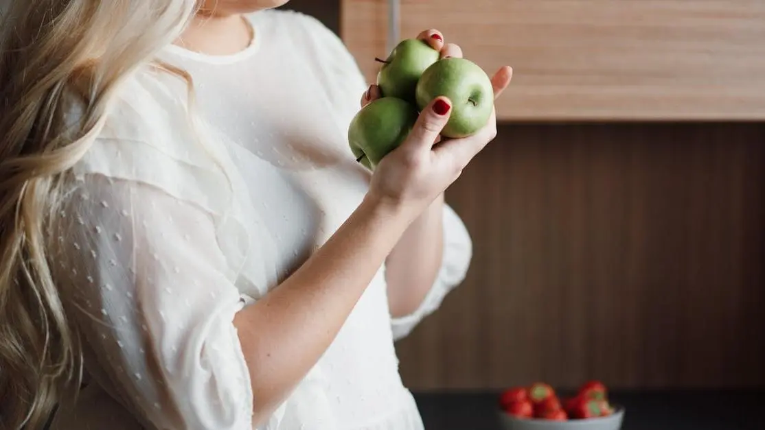 Smiling woman holding green apples, representing natural teeth bleaching with fruits and home remedies
