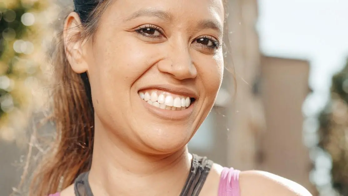 Woman smiling outdoors, showing white teeth after natural teeth whitening.